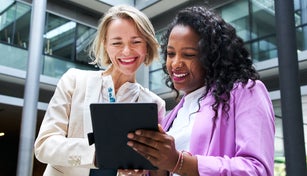 Two business women looking at a tablet computer, discussing about a business topic.