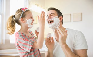 Caucasian father and daughter playing with shaving cream