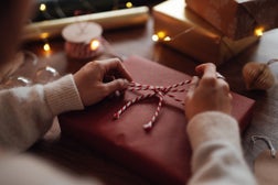 Over the shoulder view of young woman wrapping Christmas presents