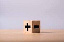 Close-Up Of Plus Minus Signs On Block