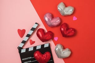 Valentine's day and romantic movie flat lay composition with  movie clapperboard and shiny heart shapes