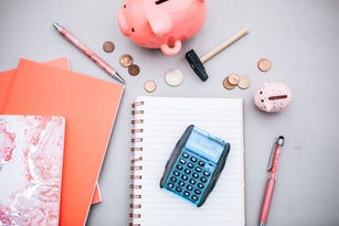 top view notebook, pencil,piggy bank calculator and coins