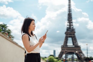 Businesswoman using smart phone while visiting Eiffel Tower in Paris on a work trip