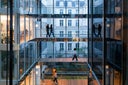 modern office building with silhouette of business women and men crossing a raised bridge on several levels in a company located in Paris