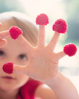 Child counting raspberries on fingers