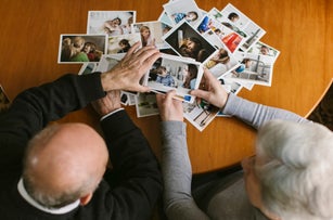 Couple reminiscing while sorting through old photographs at home
