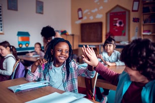 School kids high-fiving in the classroom