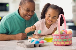 African grandfather and granddaughter coloring Easter eggs