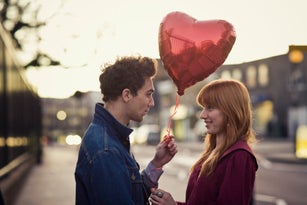Couple walking with heart-shaped balloon