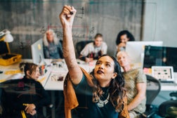 Businesswoman explaining strategy to colleagues while writing on glass at IT company