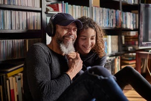 Happy father and daughter listening music with headphones together at home