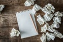 White square paper, pencil and wasted papers on wooden back ground