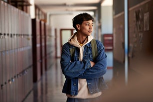 Teenage boy with arms crossed looking away in corridor