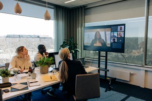 Businesswoman doing video call with male and female colleagues in conference room at office