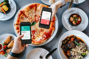 Table top view of two people splitting bill, sending / receiving payment of the meal through digital wallet device on smartphone while dining together in restaurant. Money transfer. Smart banking with technology