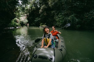 Cheerful young girl having fun on kayak with mother in rainforest, Japan