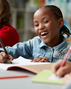 Portrait of schoolgirl drawing at the school library and laughing