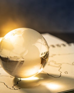 World globe crystal glass on world map outline sketch on paper page of notebook. Travel around the world. Global business or education scholarship concepts