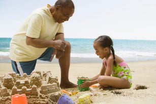 African grandfather and granddaughter building sand castle
