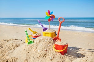 Still life of colorful beach toys and sand castle at sea against blue sky