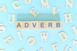 Adverb or adverbs concept in English grammar and learning class lesson. Wooden blocks typography word flat lay in blue background.