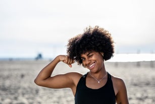 Fit woman on the beach flexing her biceps
