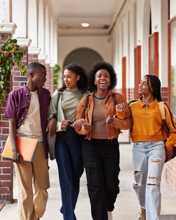 Happy friends talking while walking with arms in arms
