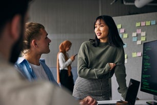 Businesswoman discussing ideas with colleagues in meeting at tech startup office