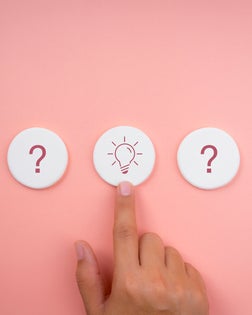 The solution, creative idea, and innovation, searching answer for success concepts, minimal style. Light bulb and question mark icon symbol on white round sponge with choosing hand on pink background.