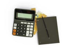 3D rendering of a composition of Comorian franc notes, a calculator, a note book and a pen isolated on white background. Tax background design concept