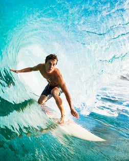 Close-up of a surfer riding a large blue wave