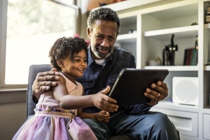 Granddaughter showing grandfather how to use tablet