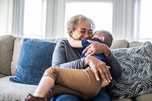 Grandmother embracing toddler grandson and laughing