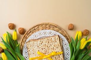 Jewish holiday Passover concept with matzah, seder plate and yellow tulip flowers on modern background