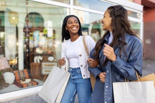 Two women friends with shopping bags walking in the city