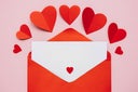 Empty Valentine card with red envelope and paper hearts on pink backgrount