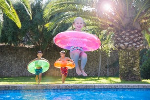 Girl jumping with inflatable ring into garden swimming pool