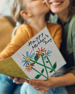 Close-up of woman receiving Mother's day greeting card from her daughter.