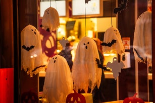 Bright, spooky city store decorated for Halloween. Street decoration. Scary ghosts window, bat, web
