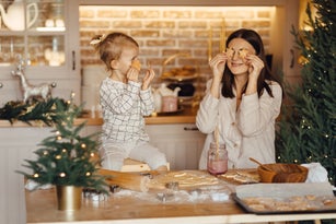 Happy daughter and beautiful mother preparing Christmas cookies in kitchen at home.
