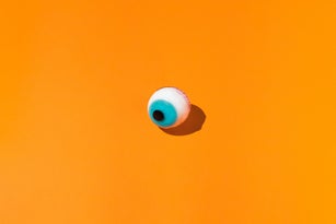 Halloween candy ghoulish eye  on orange background. Halloween and horror celebration concept.