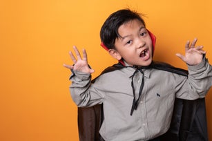 the studio portrait shot of the Asian boy with Halloween costume and the orange backdrop
