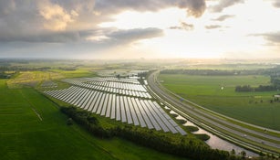 Panoramic aerial photo of solar energy panel fields along a motorway