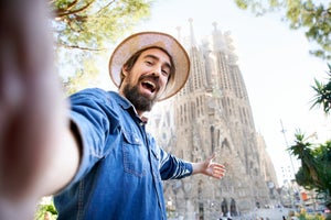 Handsome Caucasian man taking a selfie with the Sagrada Familia behind him