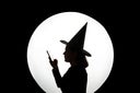 Silhouette of witch in hat with large full moon and smartphone