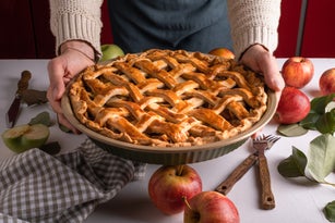 Woman holding and showing tasty cooked apple pie ready to eat, classic thankgiving tart