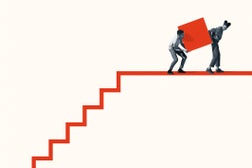 Woman and man carrying large block on staircase