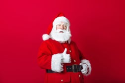 santa claus showing thumbs up gesture on red background