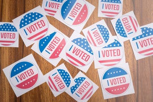 Multiple I Voted stickers on table - concept of voter fraud showing many I voted stickers.