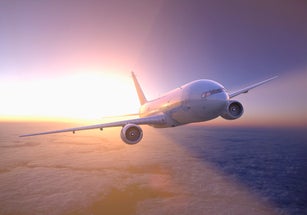 Airplane flying above clouds at sunset